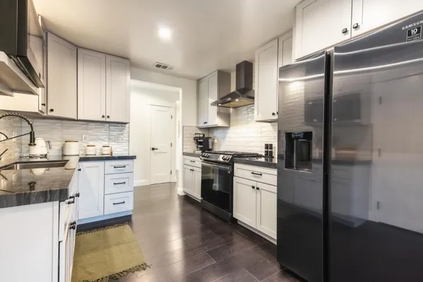 a kitchen with stainless steel appliances granite countertop a refrigerator a stove and a sink