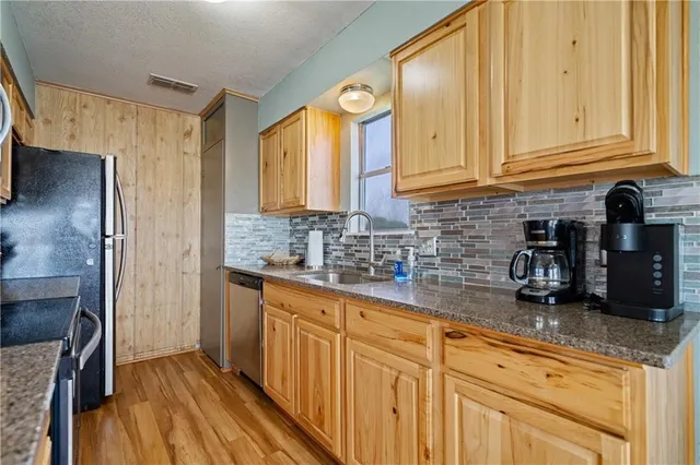 a kitchen with stainless steel appliances granite countertop a sink a stove and a wooden cabinets