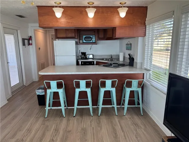 a kitchen with stainless steel appliances granite countertop a table chairs in it and wooden floors