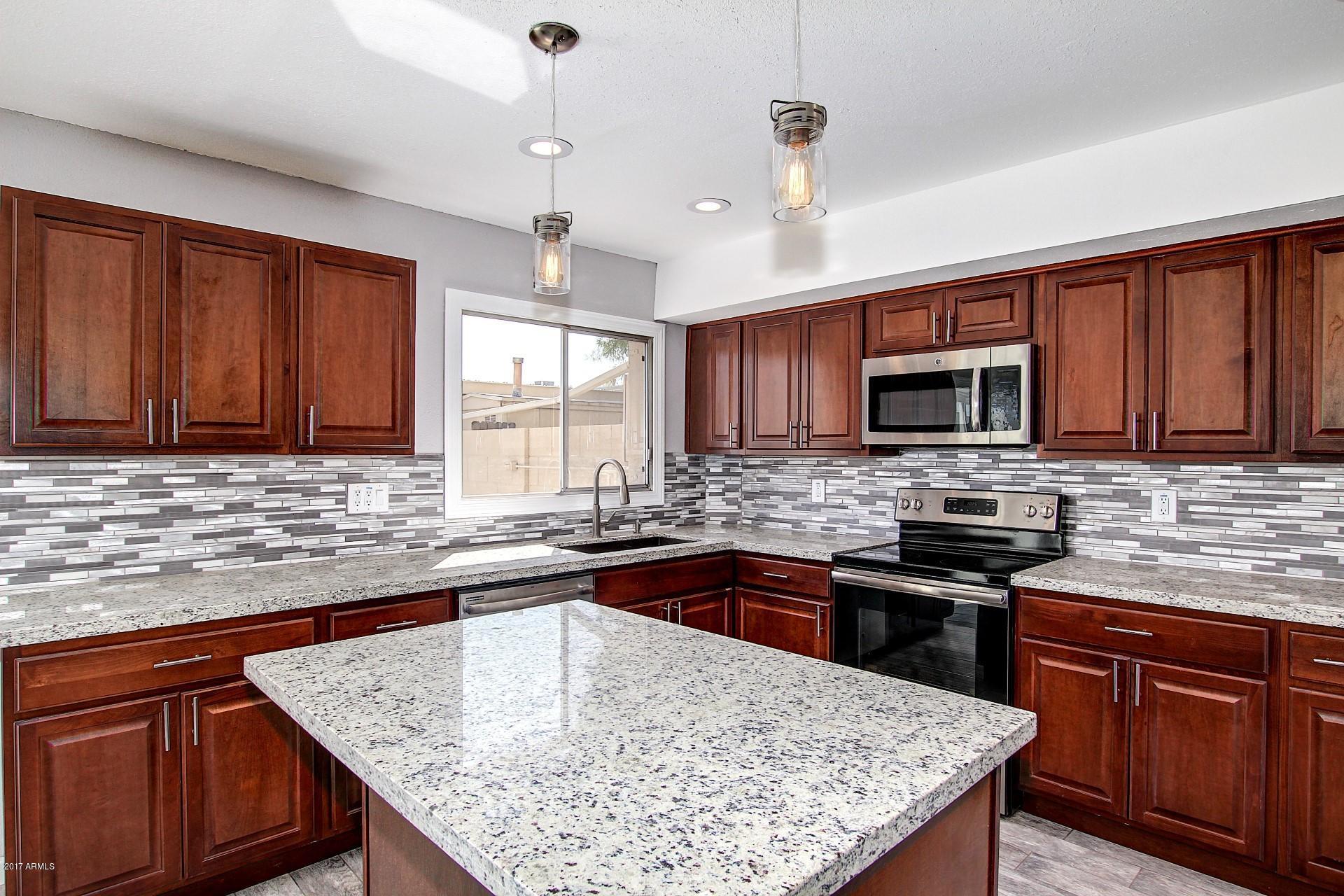a kitchen with stainless steel appliances granite countertop a sink stove microwave and refrigerator