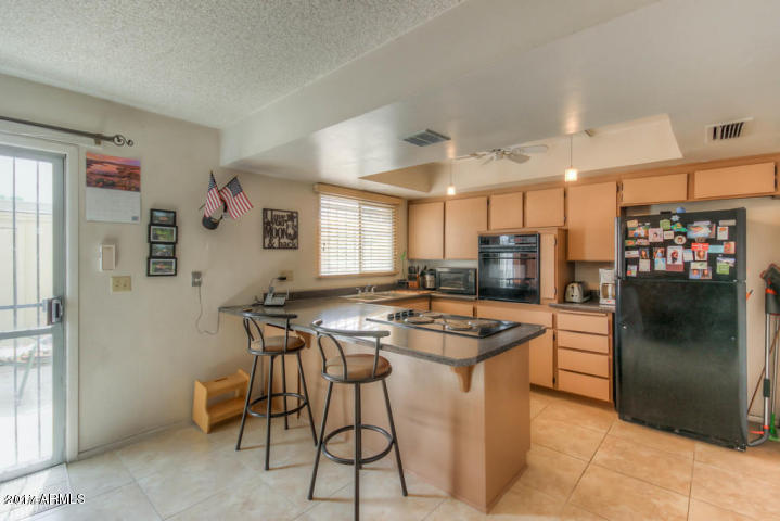 6909 East Osborn Road, Unit F Scottsdale, AZ 85251 - Photo 49 of 55 a kitchen with stainless steel appliances granite countertop table chairs and a refrigerator