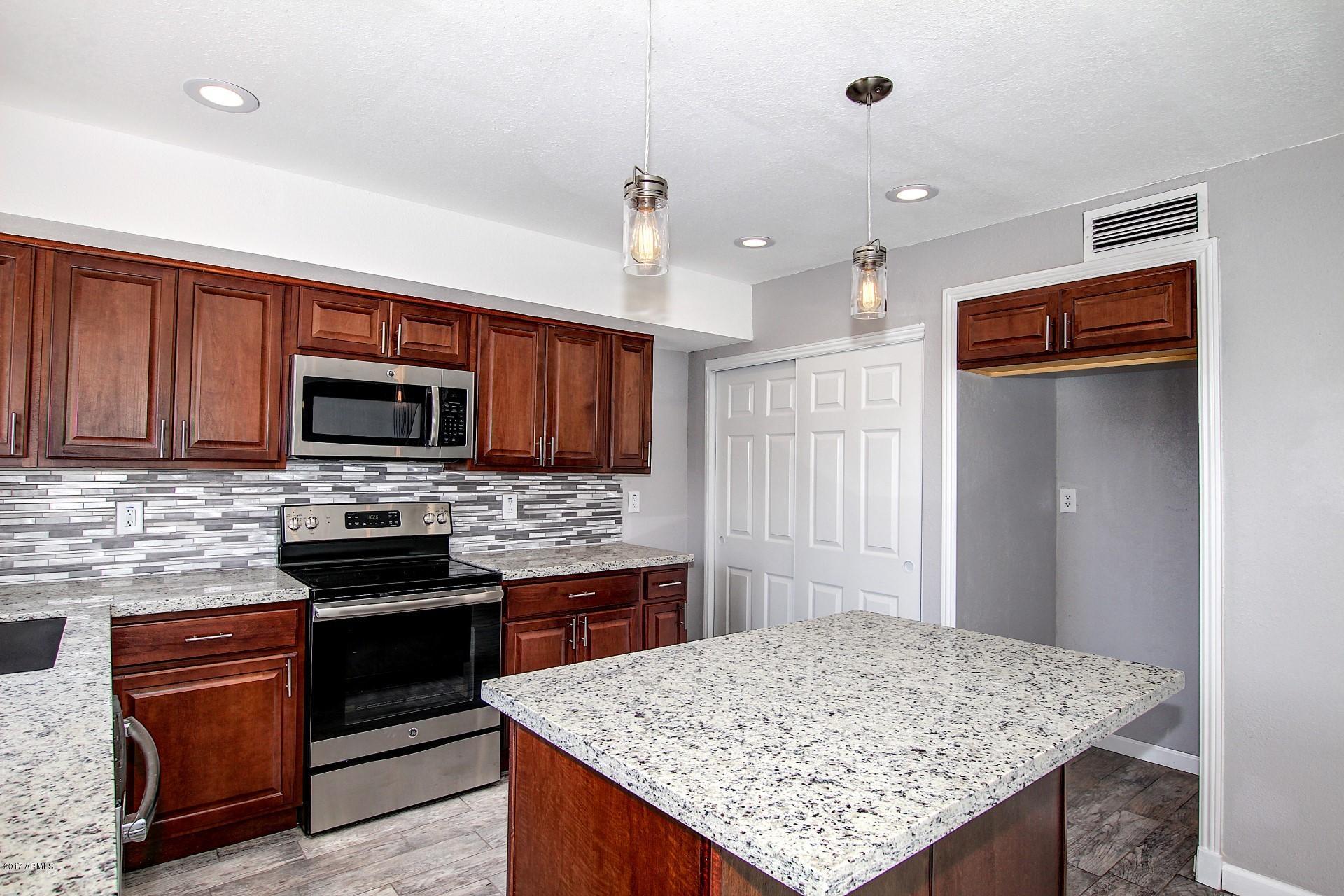 6909 East Osborn Road, Unit F Scottsdale, AZ 85251 - Photo 5 of 55 a kitchen with stainless steel appliances kitchen island granite countertop a stove refrigerator sink and microwave