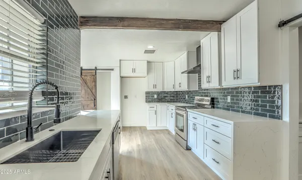 a kitchen with stainless steel appliances kitchen island granite countertop a sink stove and refrigerator