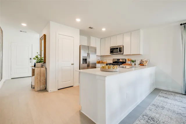 a kitchen with stainless steel appliances granite countertop a refrigerator a stove a sink a microwave and a refrigerator