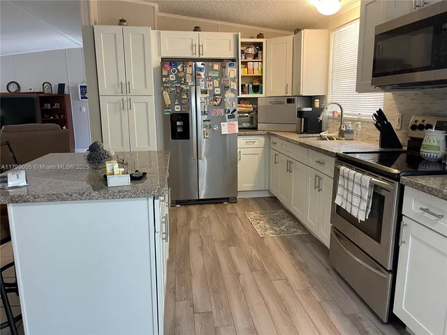 a kitchen with stainless steel appliances granite countertop a refrigerator a stove and a sink