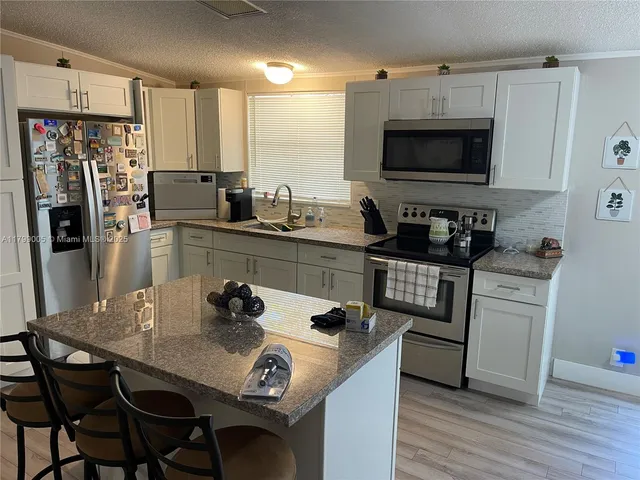 a kitchen with stainless steel appliances a table chairs and a refrigerator
