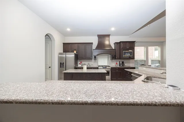 a large kitchen with stainless steel appliances granite countertop a sink a stove and a refrigerator