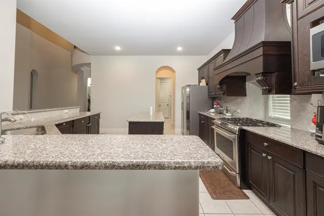 a large kitchen with granite countertop a sink and stainless steel appliances