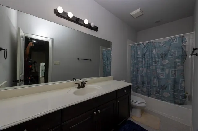 a bathroom with a sink a toilet a mirror and shower