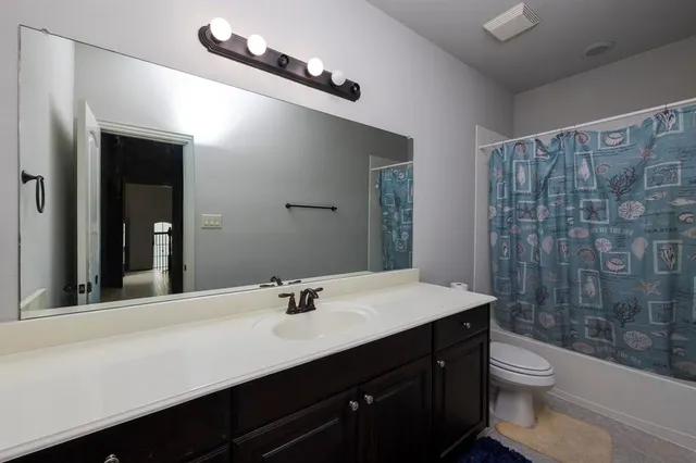 a bathroom with a sink a toilet a mirror and shower