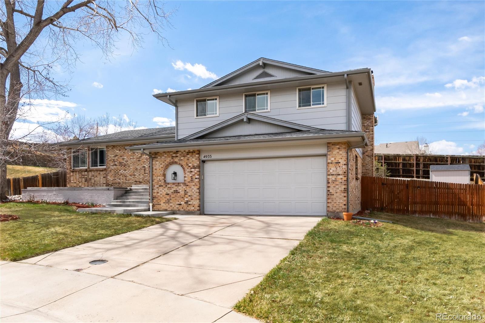 4935 South Routt Street Littleton, CO 80127 - Photo 3 of 45 a front view of a house with a yard and garage