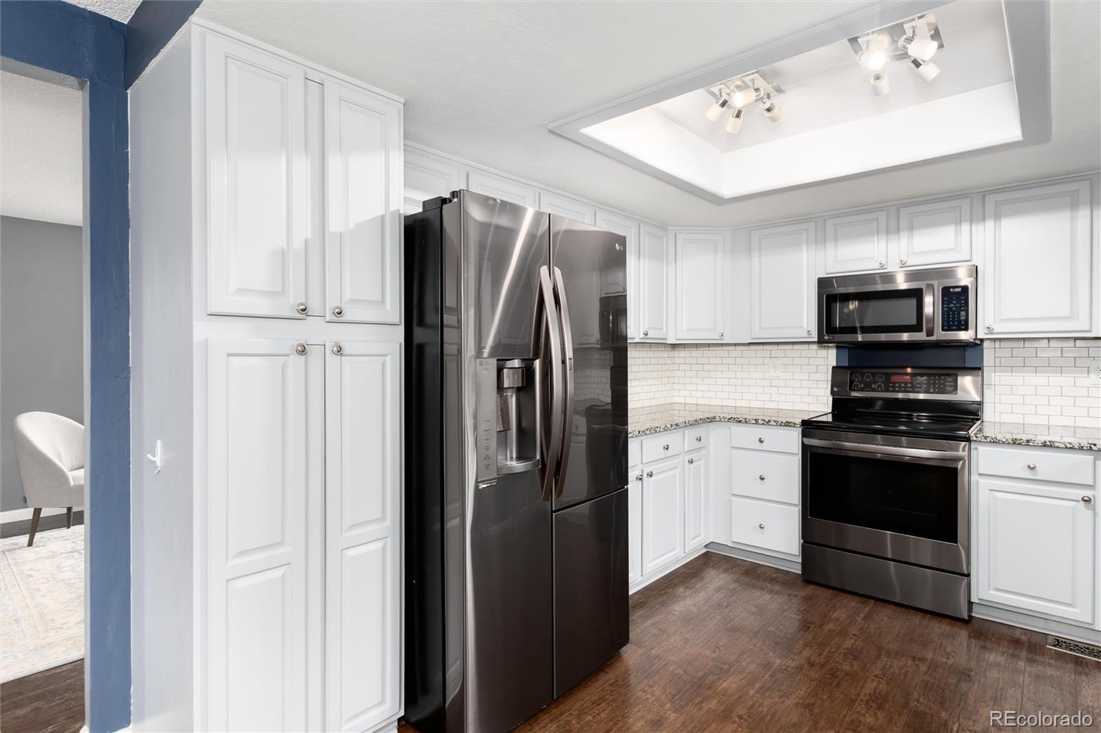 4935 South Routt Street Littleton, CO 80127 - Photo 10 of 45 a kitchen with stainless steel appliances granite countertop a refrigerator stove and sink