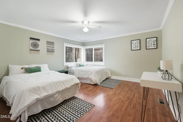 a bedroom with two beds and a wooden floor