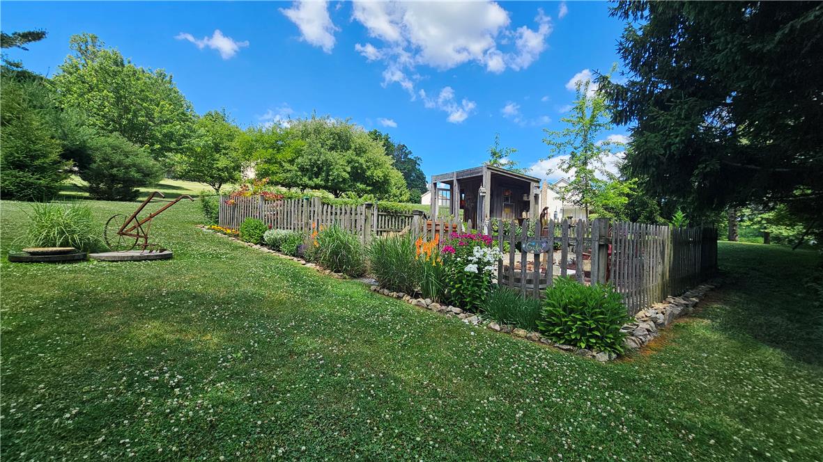 585 Buttermilk Road Hellertown, PA 18055 - Photo 51 of 82 A quaint garden with blooming flowers and a wooden fence creates an inviting outdoor retreat.