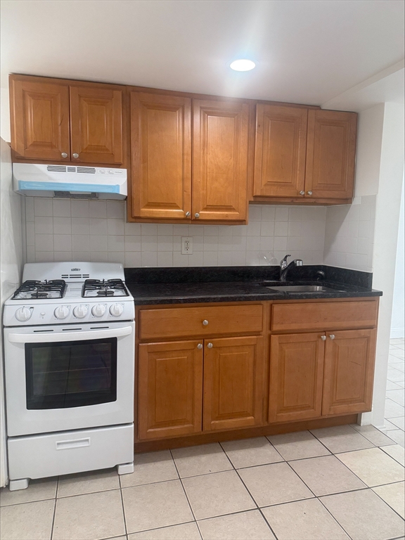 104 Beacon Street, Unit 1A Chelsea, MA 02150 - Photo 7 of 9 a kitchen with granite countertop white cabinets and white appliances