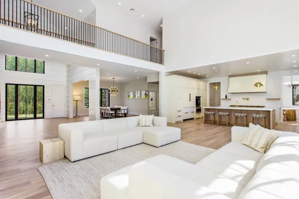 a living room with furniture large windows and wooden floor