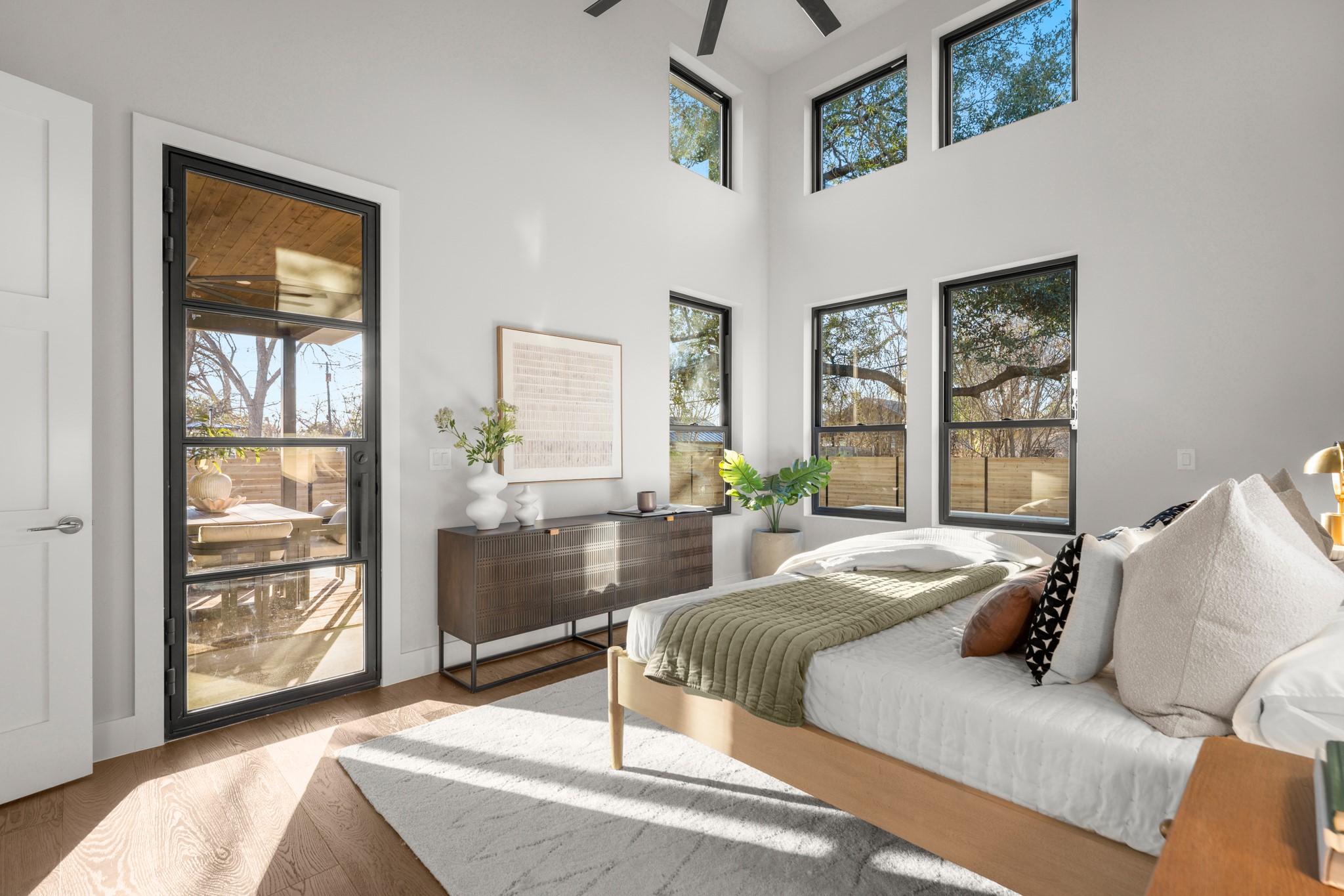 7706 Rutgers Avenue Austin, TX 78757 - Photo 11 of 35 Bedroom with access to exterior, wood finished floors, multiple windows, and a high ceiling
