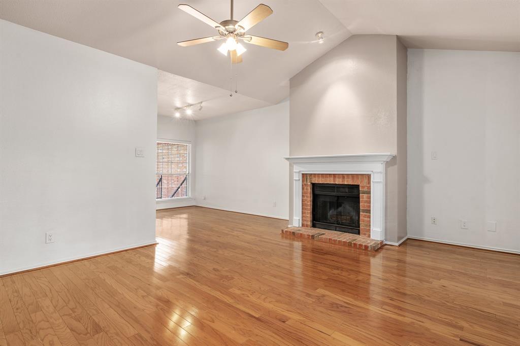 12660 Hillcrest Road, Unit 4203 Dallas, TX 75230 - Photo 4 of 16 Unfurnished living room with lofted ceiling, ceiling fan, light wood-type flooring, and a fireplace