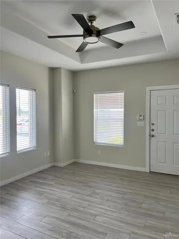 an empty room with wooden floor and windows