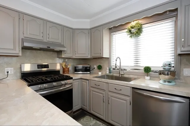 a kitchen with white cabinets appliances a sink and a window
