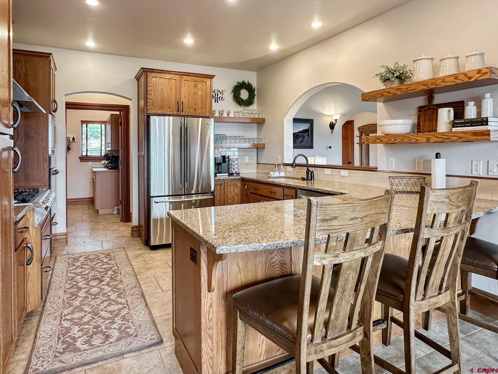 1787 Roubideau Street Delta, CO 81416 - Photo 14 of 35 a kitchen with stainless steel appliances granite countertop table chairs and a refrigerator