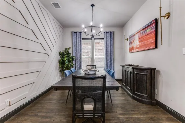 a dining room with wooden floor a chandelier a wooden table and chairs