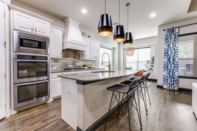 a kitchen with stainless steel appliances granite countertop a stove a sink and a microwave