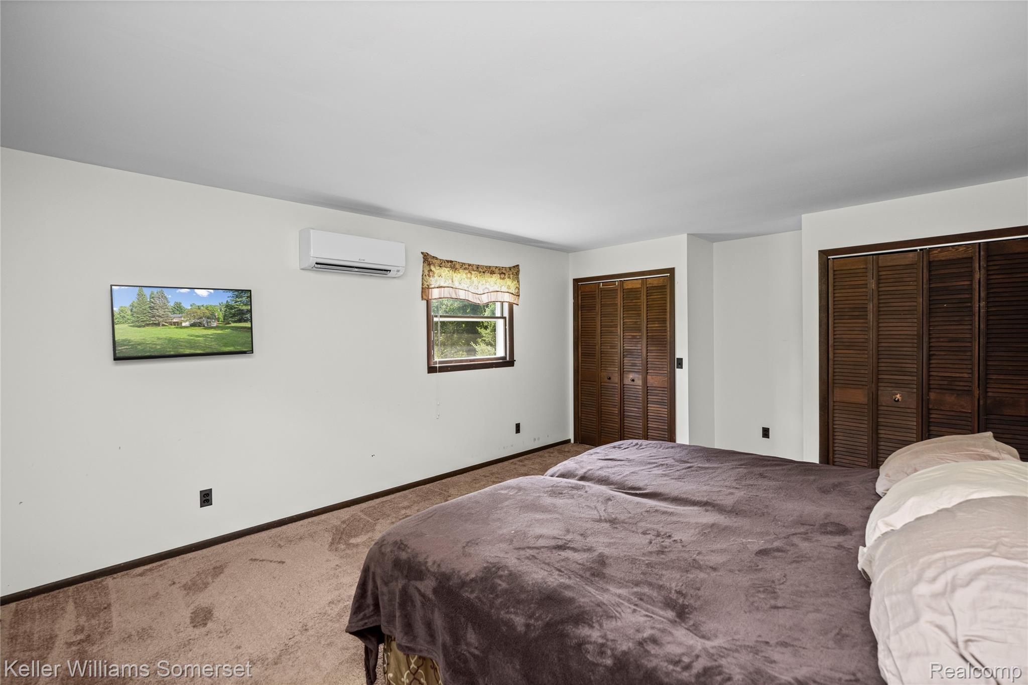 2344 Rochester Road Leonard, MI 48367 - Photo 26 of 66 Room featuring wall-mounted climate control unit, a window with exterior visibility, and two sets of louvered bifold closet doors