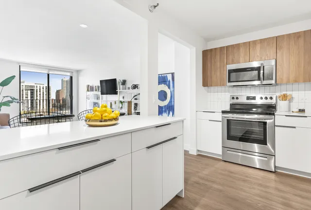 a kitchen with stainless steel appliances a stove a sink a refrigerator white cabinets and wooden floor