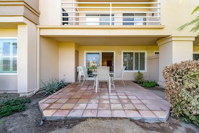 a patio with table and chairs and potted plants
