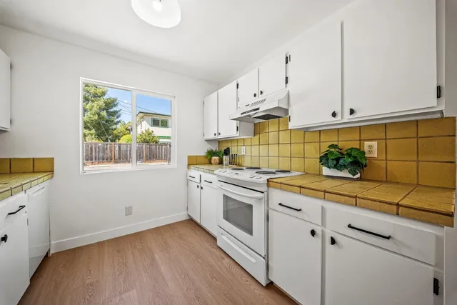 a kitchen with stainless steel appliances white cabinets and a window