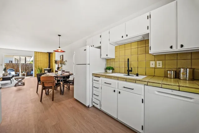 a kitchen with stainless steel appliances a table chairs refrigerator and cabinets