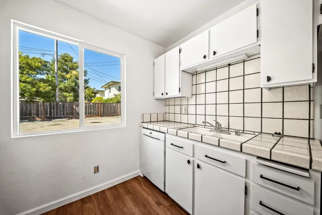 a view of a kitchen with fridge and wooden floor
