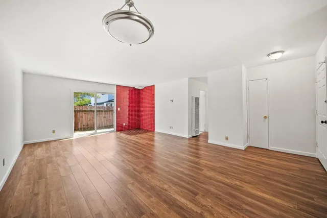 a view of an empty room with wooden floor and cabinets