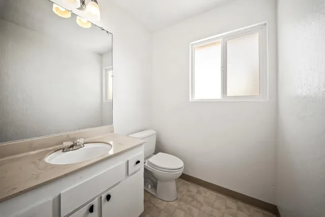 a bathroom with a granite countertop sink a toilet and a mirror