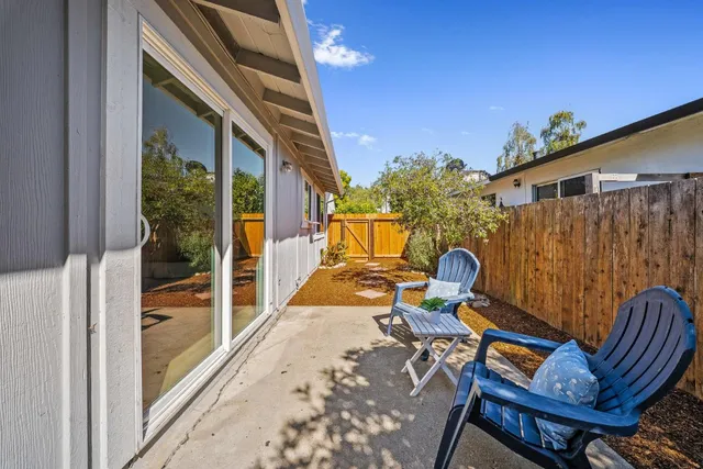 a view of a patio with table and chairs with wooden floor and fence