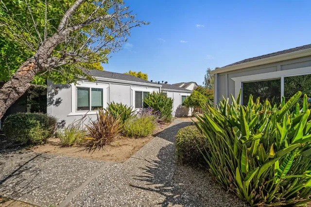 a view of a house with a small yard and potted plants