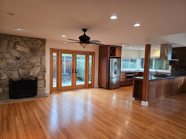 a view of an empty room with wooden floor and a fireplace