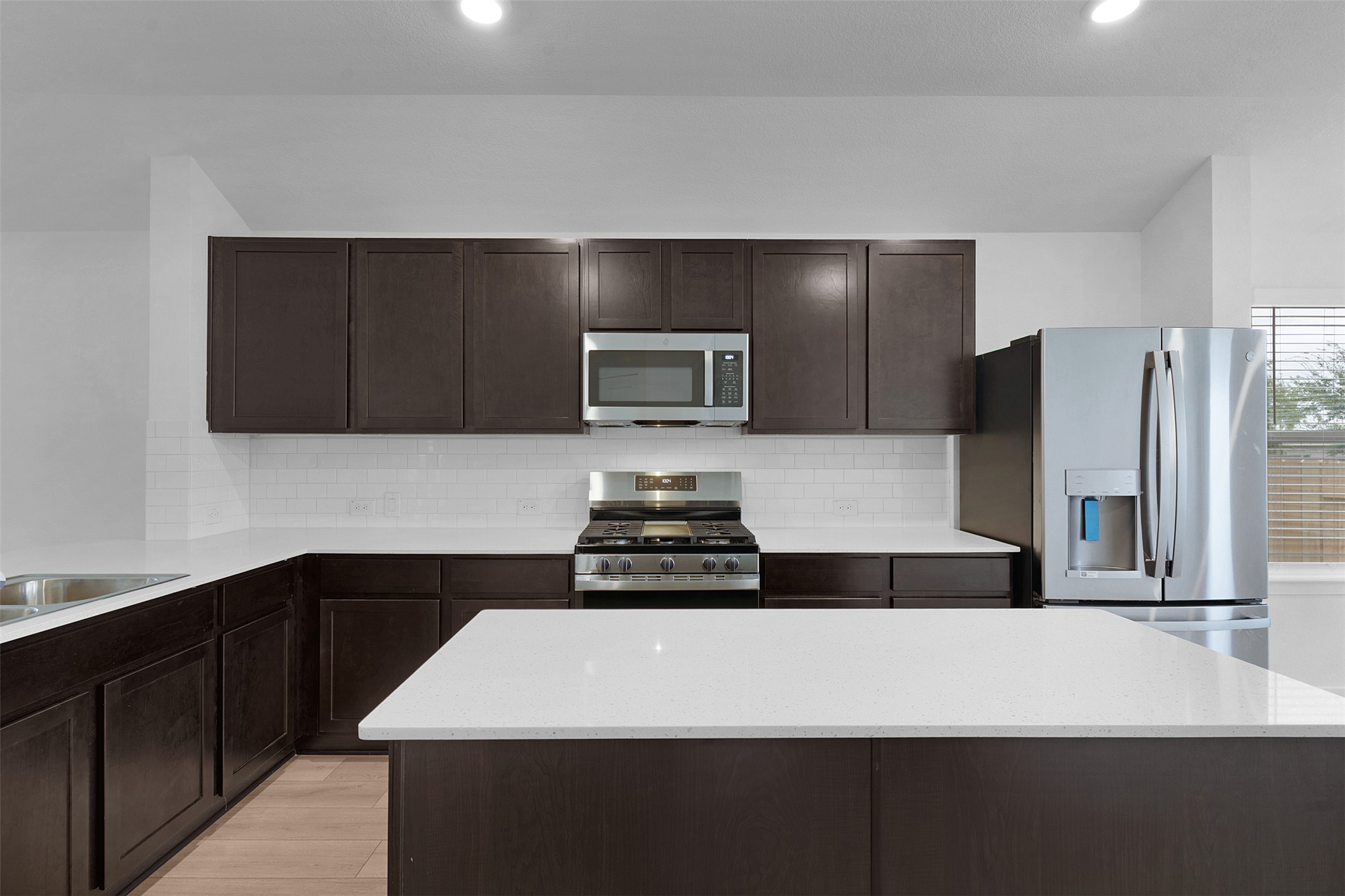 13721 Tucker Hedge Pass Elgin, TX 78621 - Photo 8 of 28 Kitchen with dark brown cabinetry, appliances with stainless steel finishes, tasteful backsplash, a kitchen island, and recessed lighting