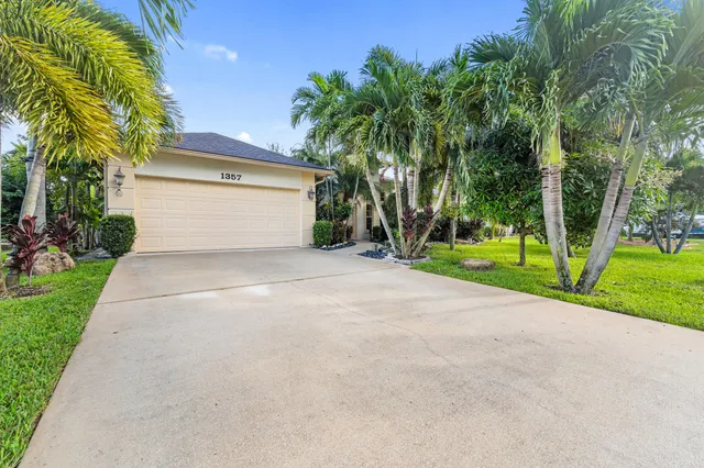 a view of a house with a yard and palm trees