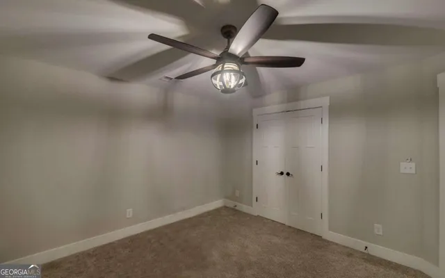 an empty room with a ceiling fan and carpet