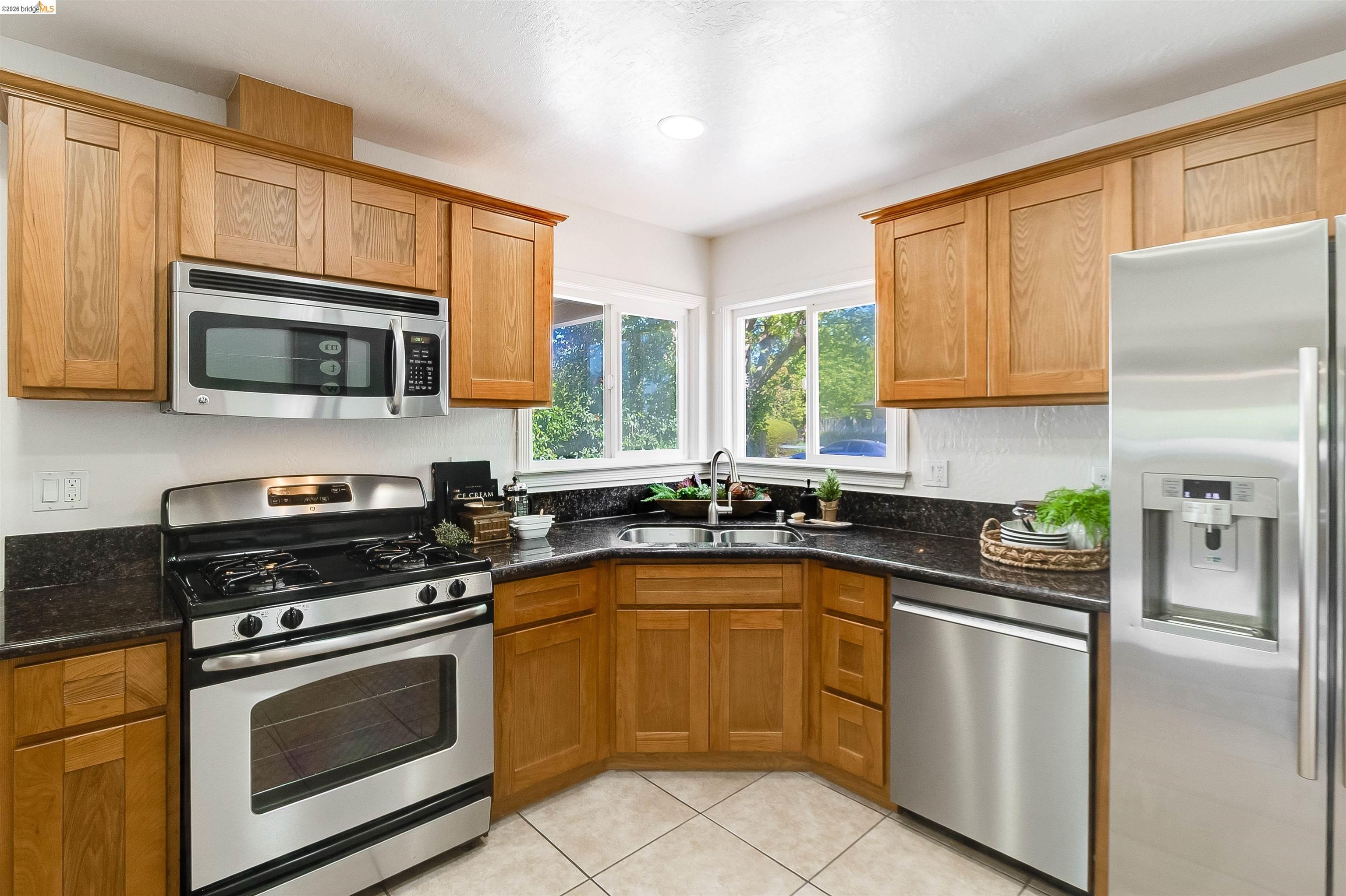 346 Valley View Road Pleasant Hill, CA 94523 - Photo 15 of 57 Kitchen featuring wood cabinetry, stainless steel appliances, dark countertops, and tile flooring