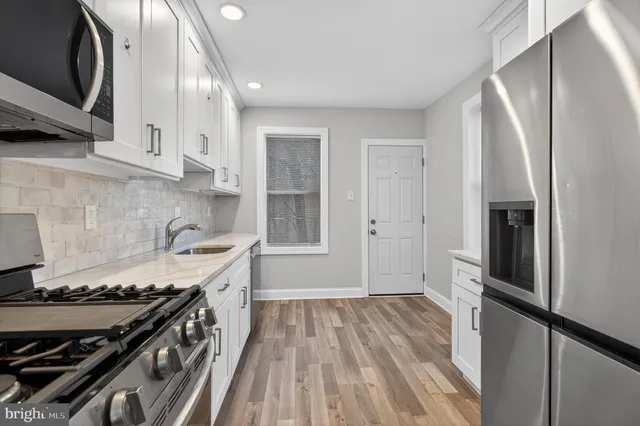 a kitchen with stainless steel appliances granite countertop a refrigerator sink and wooden cabinets