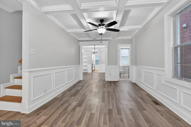 a view of empty room with wooden floor and fan