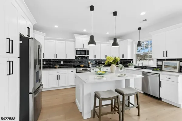 a kitchen with stainless steel appliances kitchen island granite countertop a table chairs and a refrigerator