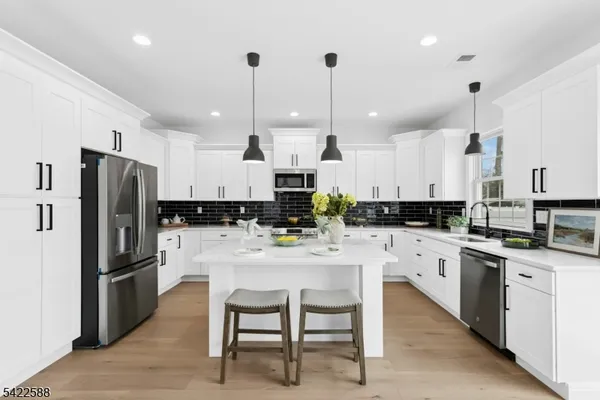 a kitchen with stainless steel appliances kitchen island a refrigerator a stove a sink a dining table and chairs