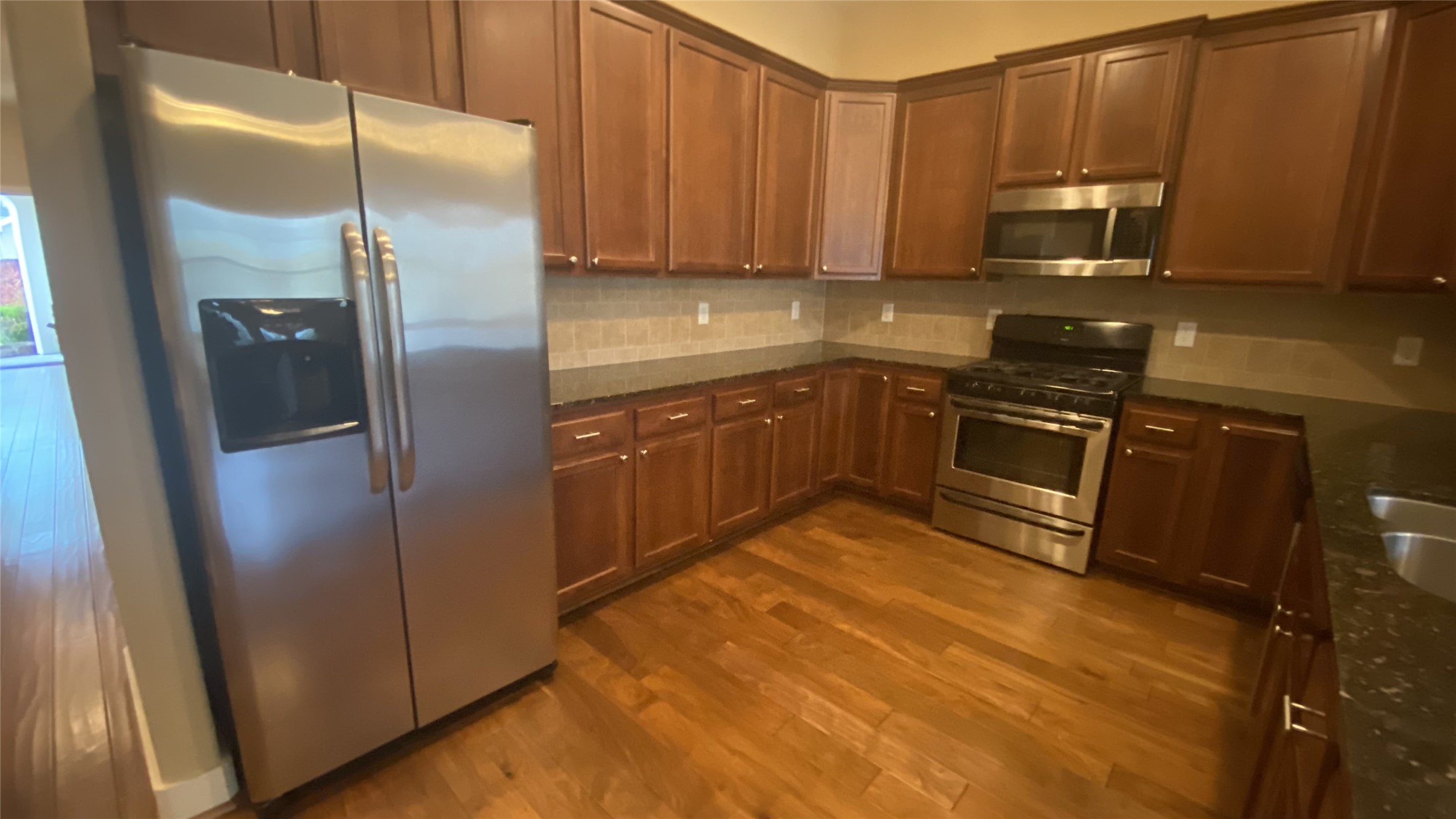 6057 Yale Street Houston, TX 77076 - Photo 18 of 49 a kitchen with stainless steel appliances granite countertop a refrigerator a stove and a sink with wooden cabinets
