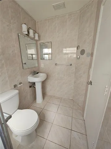 a white toilet sitting next to a bathroom sink and a mirror