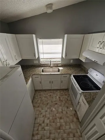 a kitchen with a sink a stove top oven and cabinetry