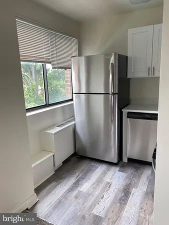 a close view of a refrigerator in kitchen with stainless steel appliances wooden floor